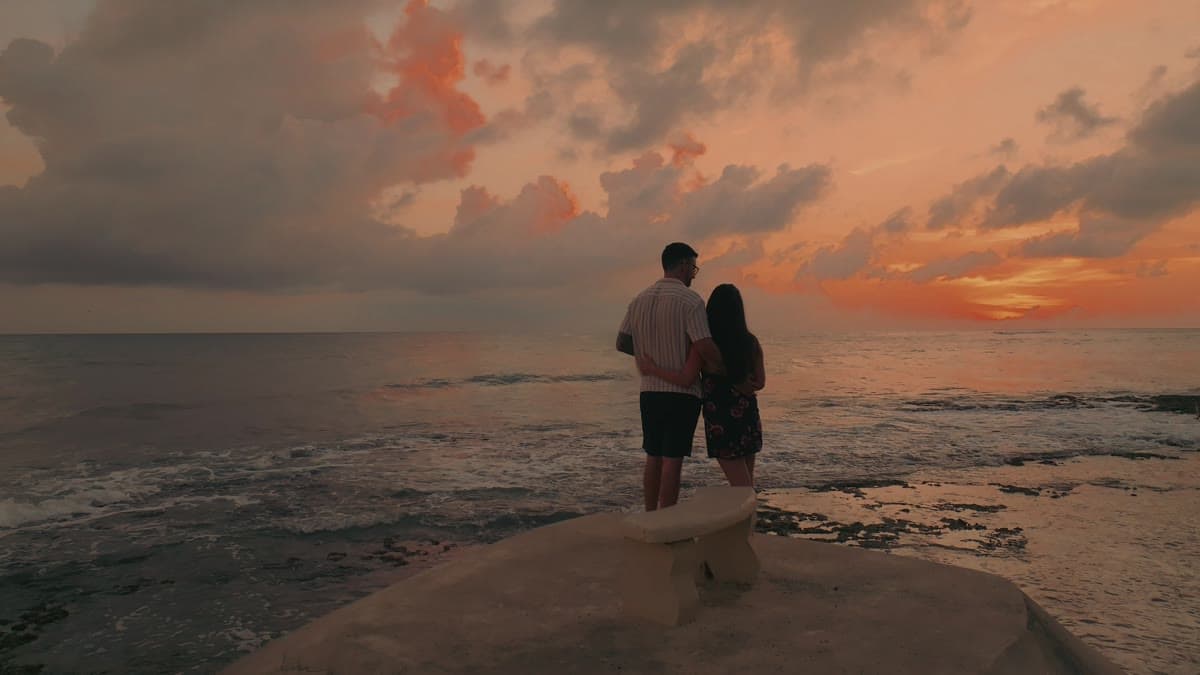 A couple walking out along the ironshore at sunset