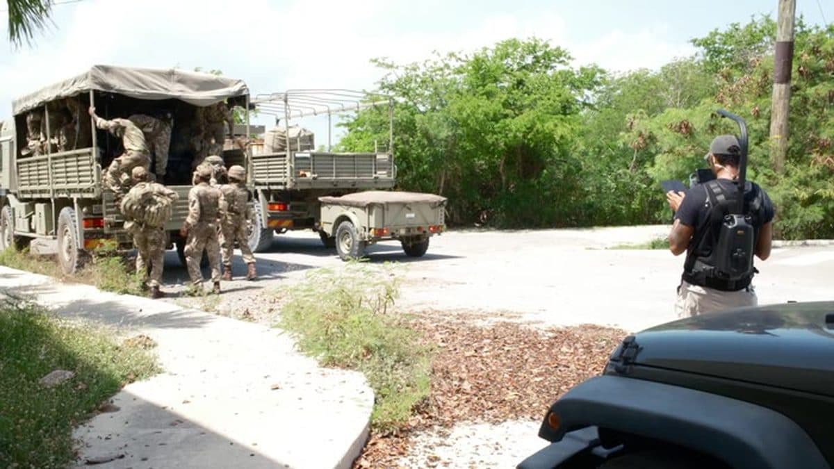 Soldiers unloading equipment from a truck while a camera operator films