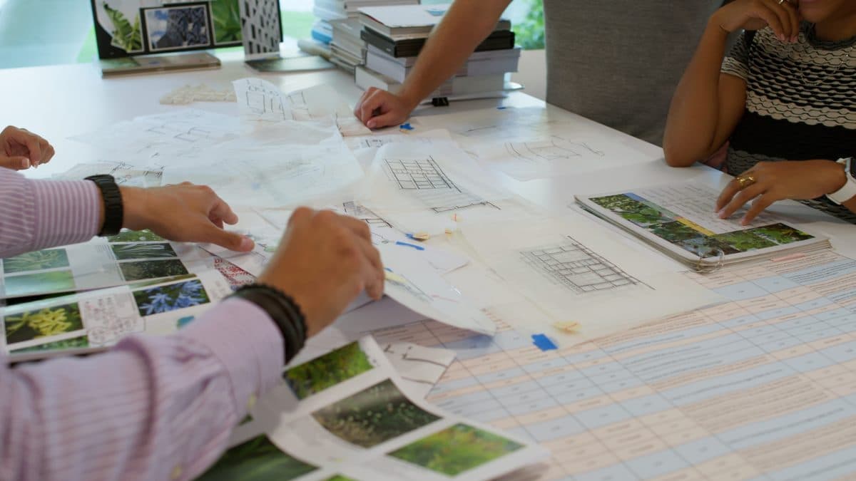 Hands over architectural plans and site photographs